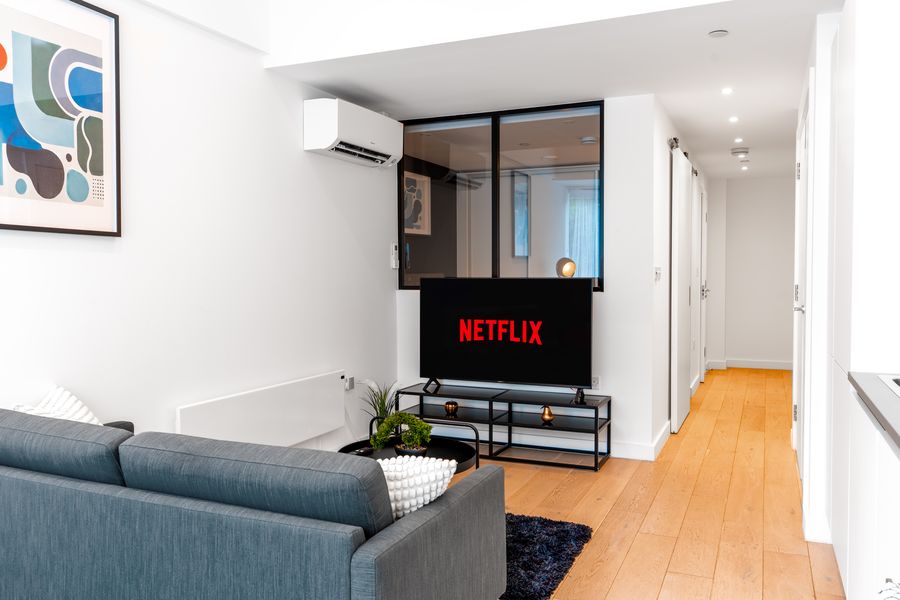 Living room with a grey sofa, TV and a view down the hallway