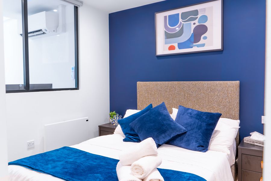 Double bed with blue cushions against a navy wall