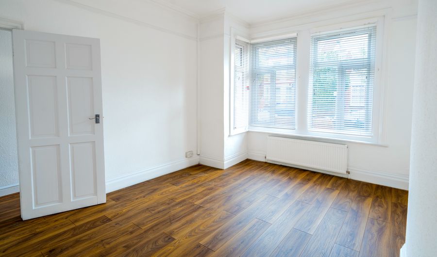 Living room with bay windows, white walls and a wooden floor