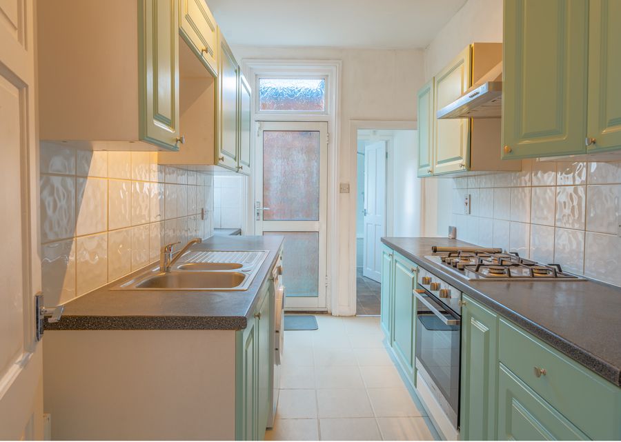 Galley kitchen with sage green cabinets and dark worktops