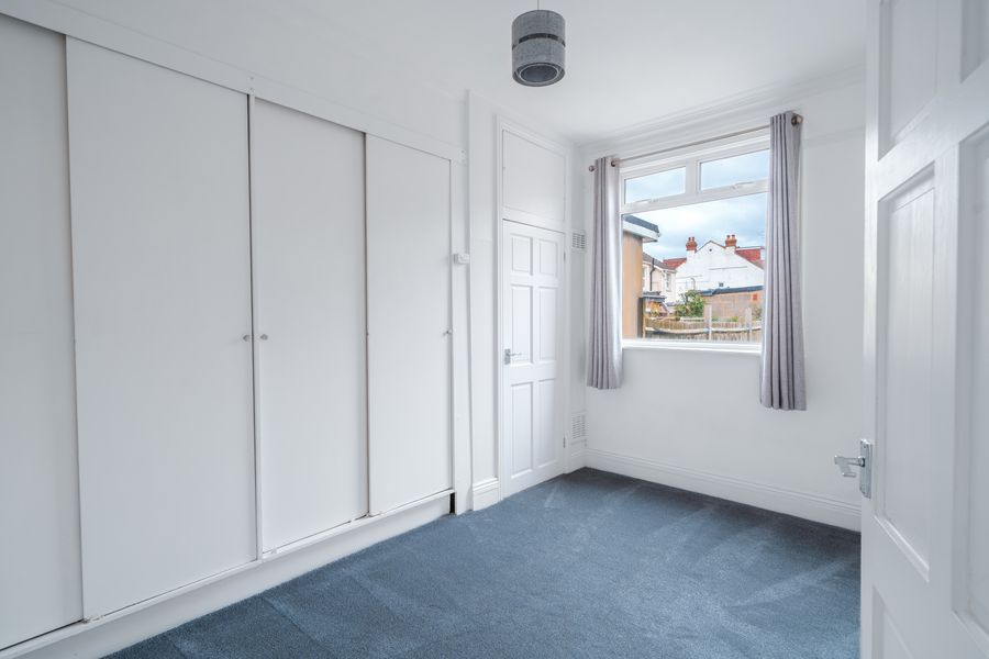 Bedroom with fitted wardrobes, grey carpet and a window