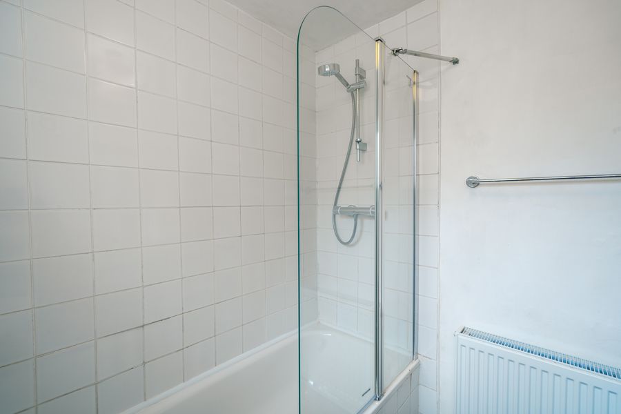 Bath with a glass shower screen and white tiles