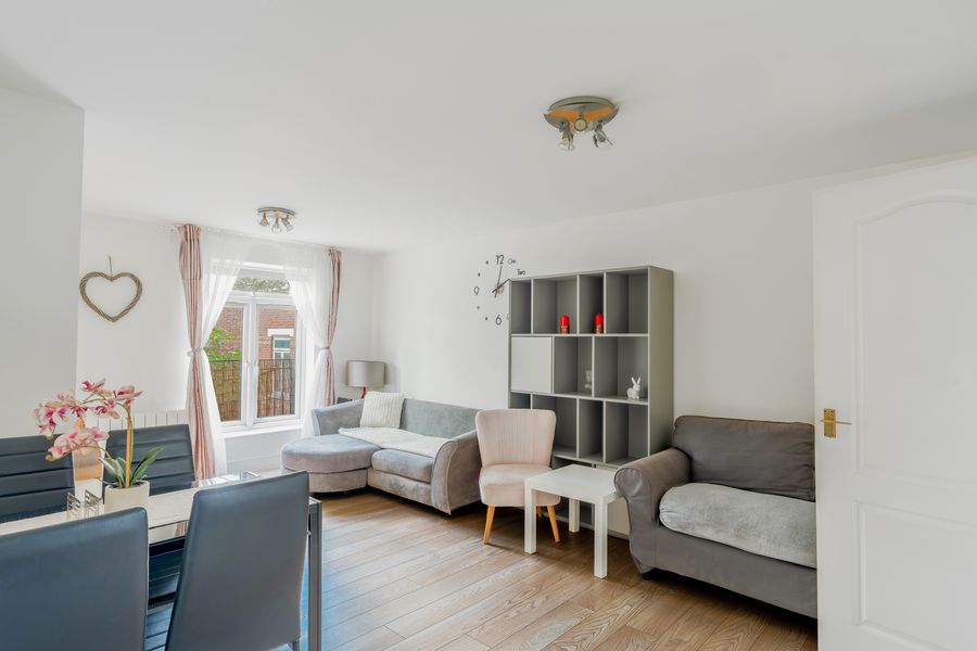 Living room with grey sofas, a wooden floor and a tall window