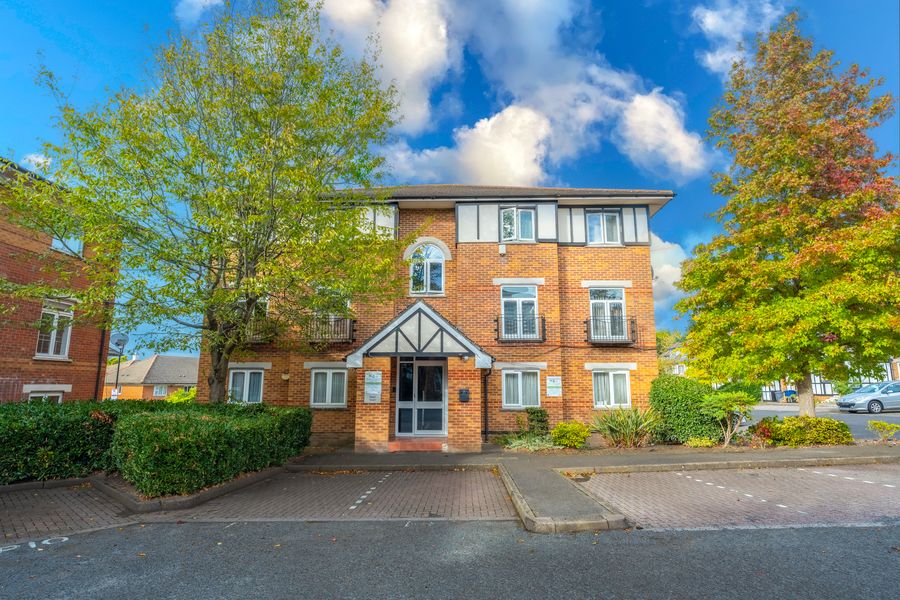 Brick block of flats with trees under a blue sky